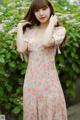 A woman in a pink floral dress posing for a picture.