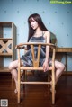 A woman sitting on a wooden chair in a room.