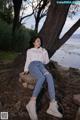 A woman sitting on a rock by the water.