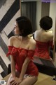 A woman in a red lingerie sitting in front of a mirror.