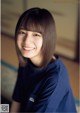 A woman in a blue shirt smiles at the camera.