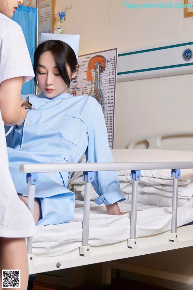A woman in a hospital bed with a nurse standing next to her.