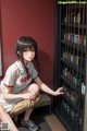 A woman sitting on the floor in front of a book shelf.