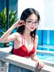 A woman in a red bikini and glasses leaning on a railing.