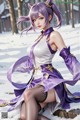 A woman in a purple and white outfit sitting in the snow.