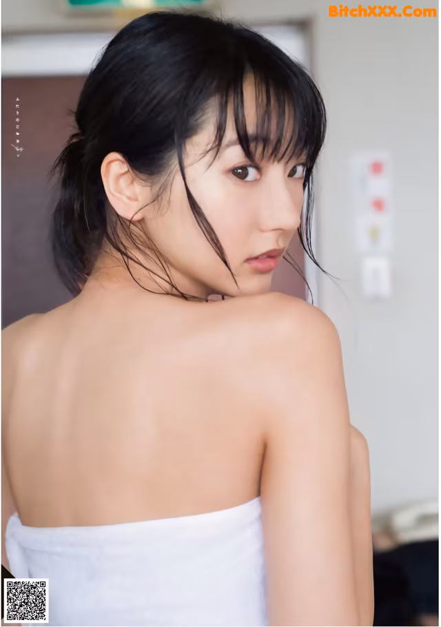 A woman in a white towel is posing for a picture.