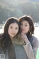 Two young women standing next to each other near a body of water.