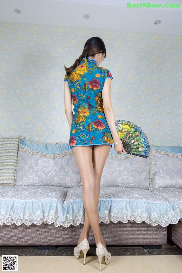 A woman in a blue dress holding a fan in her hand.