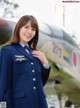 A woman in a blue uniform standing in front of an airplane.