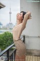 A woman in a beige shirt and polka dot skirt posing on a balcony.