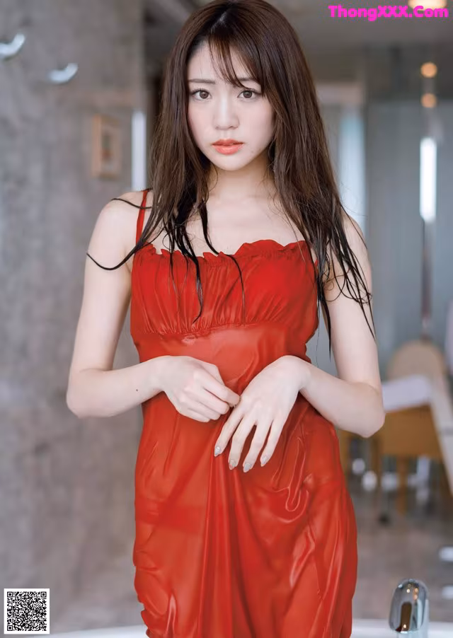A woman in a red dress standing in a bathroom.