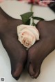 A pair of black stockings with a pink rose on top of them.