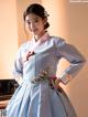 A woman in a blue hanbok is posing for a picture.