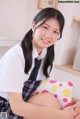 A young woman in a school uniform sitting on the floor.