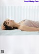 A woman laying on a bed with her head on her hands.