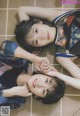 A couple of young women laying on top of a tiled floor.