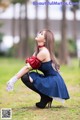 A woman in a blue dress and white gloves crouching on the ground.