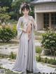 A woman in a white kimono standing in a garden.