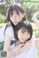 A couple of young women sitting on top of a green chair.