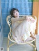 A woman sitting in a wicker chair in front of a window.