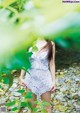 A woman in a white dress standing in the woods.