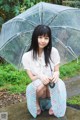 A woman sitting on a bench holding an umbrella.