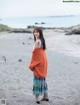 A woman standing on a beach next to the ocean.